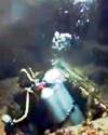 Still from Cousteau film exploring the wreck of the Britannic, showing diver coming up out of an opening in the structure.