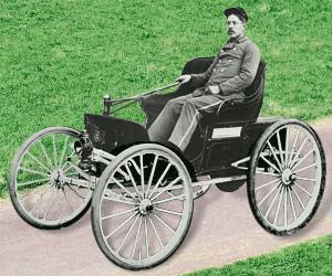 Photo of 1896 Duryea Motor Wagon, with driver. Resembles a horse-drawn open top carriage, cartwheels with spokes (no horse)