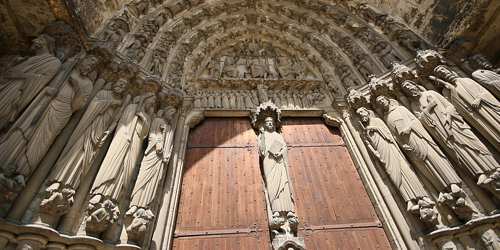 Photo of a portal of Chartres Cathedral, doors flanked by statues, arches with many smaller carvings. Credit: dozemode, pixabay)