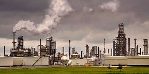 Photo large refinery, storage tanks, many tall fractionating column structures, chimney, cloud of vapor, ExxonMobil, nr Chicago