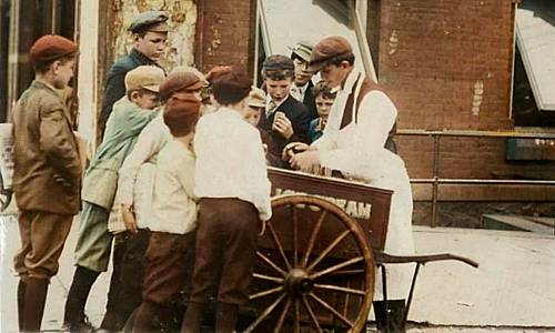 Wooden push cart with handles, vendor serving a dozen young boys wearing caps, buying ice cream. Colorization palette.fm