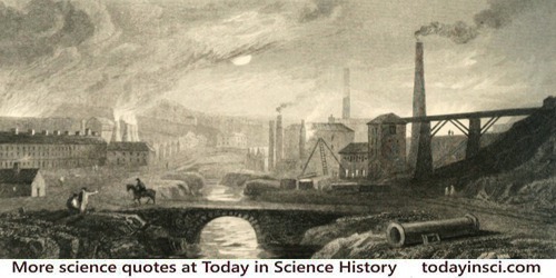 Tall smokestacks and chimneys smoking, industrial brick buildings, stream between, up through center of image, bridge foreground