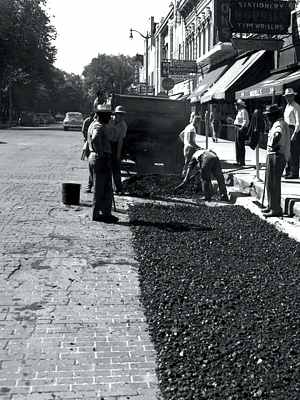 Photo of Ann Arbor MI street 1951 with workers laying asphalt being laid over brick pavers, b/w