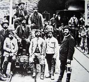 Photo of a small group of Gotthard Tunnel construction workers sitting or and standing around a small railway wagon