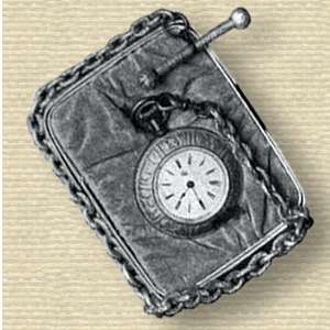 Photo of a watch with ornate bezel on a small cushion around which is wrapped its chain