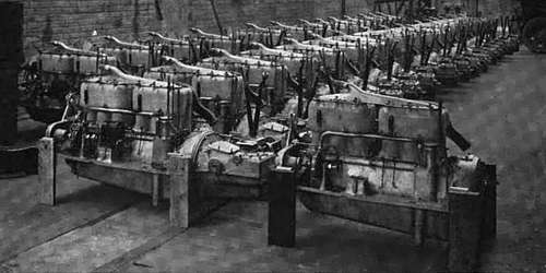 Photo of warehouse with long rows of dozens of automobile engines assembled with crankcase and transmission bell castings