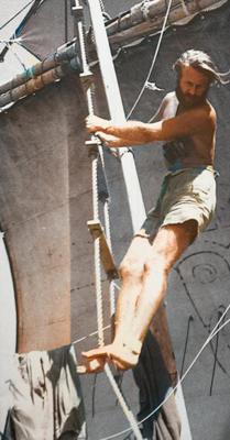Photo of Thor Heyerdahl standing on rope ladder, among sail & rigging of Kon-Tiki, credit palette.fm for colorization assistance