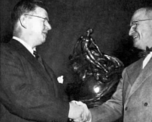 Photo of William Lear shaking hands with President Truman in front of the Collier Trophy - upper body