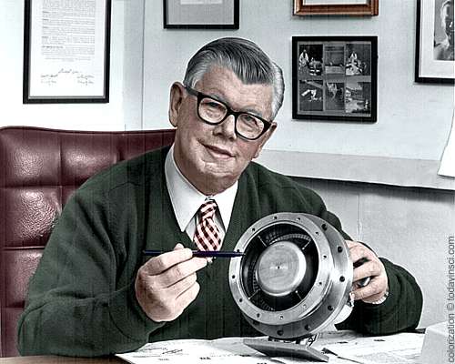 William Lear, seated behind office desk, showing turbine engine - colorization © todayinsci.com - original b/w public domain