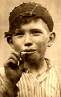 Detail from sepia photo showing cotton mill child worker John Tiddwell smoking, 3/4 body standing, face front, work clothes
