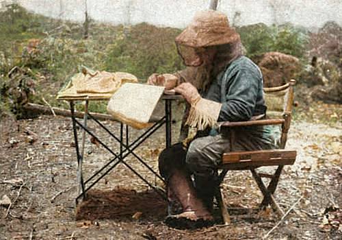 Photo of Theodore Roosevelt, while on expedition, outdoors in South America seated at a table making notes.