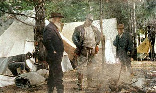 Photo of John Burroughs and Theodore Roosevelt standing in a camp with tents in the background