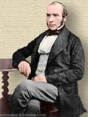 Photo of John Snow, full body seated, legs crossed, arm on side table, facing mid-left. Colorization © todayinsci.com