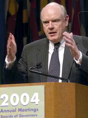 Photo John W. Snow upper body facing front seen behind stage podium addressing 2004 Boards of Governors Meeting