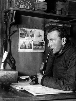 Photo of Alfred Wegener behind desk, b/w, upper body, facing left, smoking pipe, Greenland base