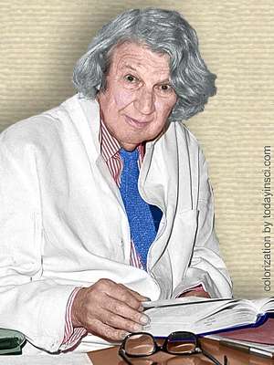 Photo of John Z Young seated behind office desk, upper body facing front. Colorization by todayinsci.com